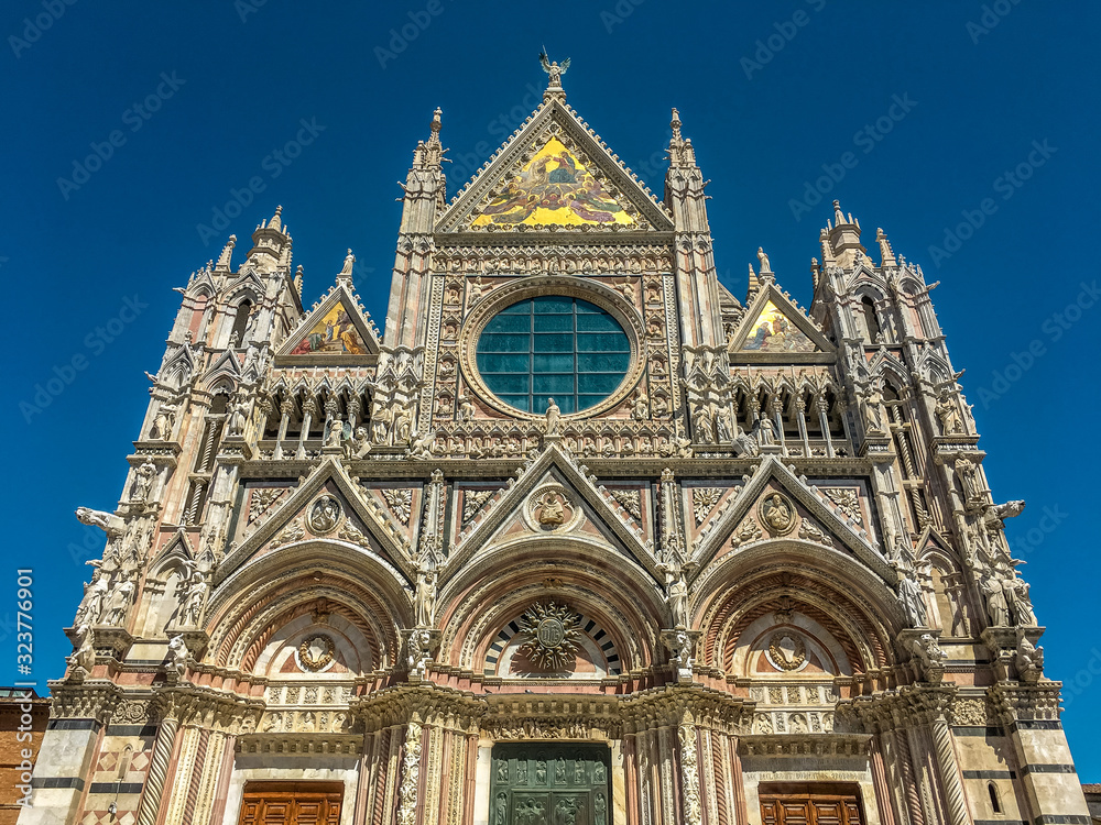 Main Facade of Duomo di Siena—13th-century Romanesque-Gothic Cathedral with mosaics and marble stripes on facade.