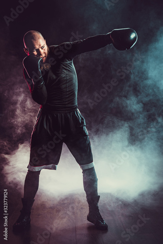 Sportsman boxer fighting on black background with smoke. Boxing sport concept.