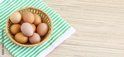 Real farm chicken eggs lie in a wicker basket on the table. Green striped napkin