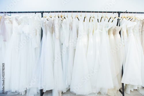 Horizontal no people shot of beautiful wedding dresses on clothes rails in modern bridal dress-making studio