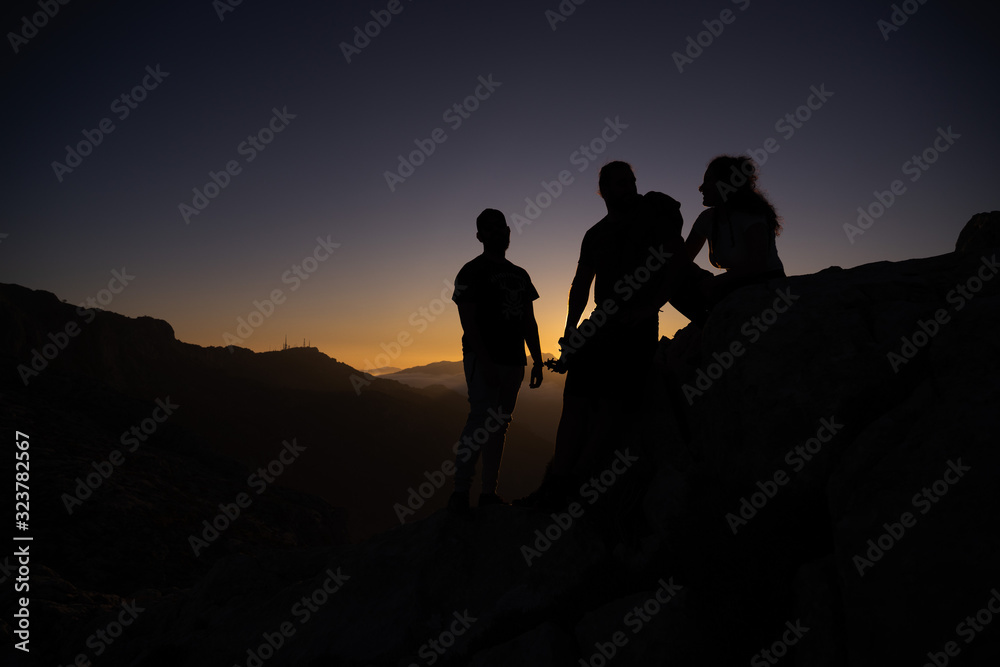 Silhouette of a group of friends on some rocks during sunset