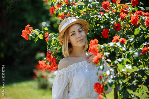 girl in a hat in the garden of a red rose