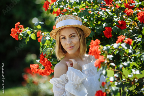 girl in a hat in the garden of a red rose