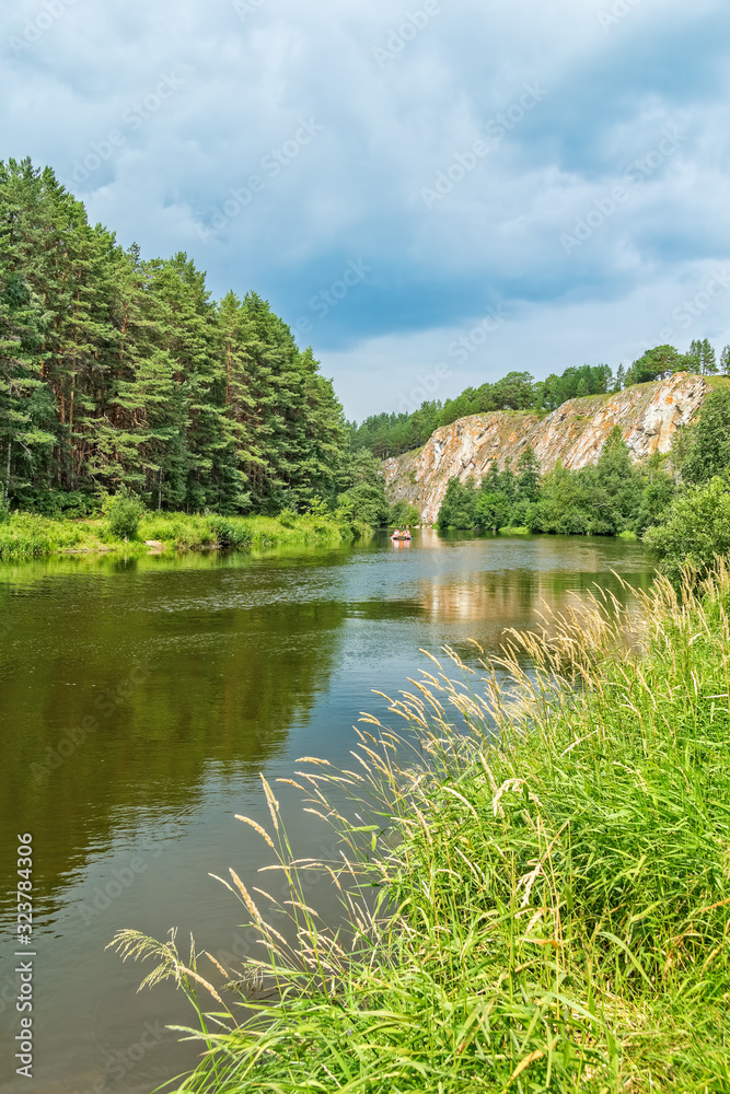 Green grass on the riverbank against the rocks