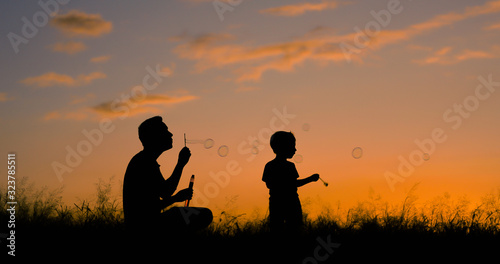 Happy father and son having fun playing bubbles in the park. 