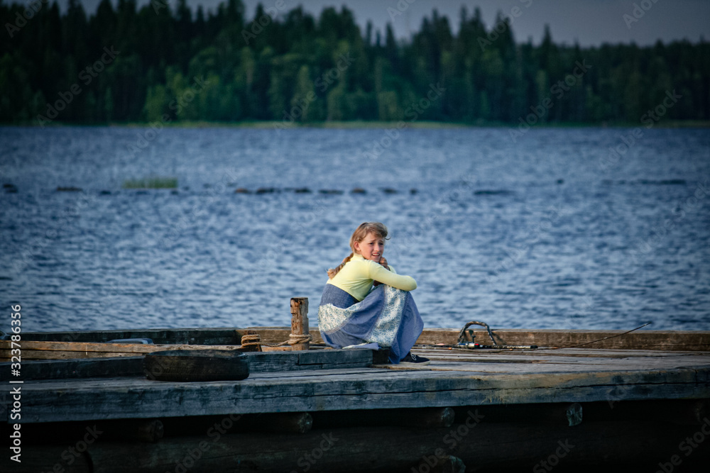 Girl sits on a wooden pier of the lake Girl sits on a wooden pier of the lake