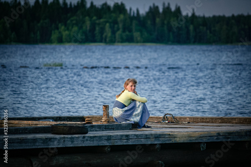 Girl sits on a wooden pier of the lake
