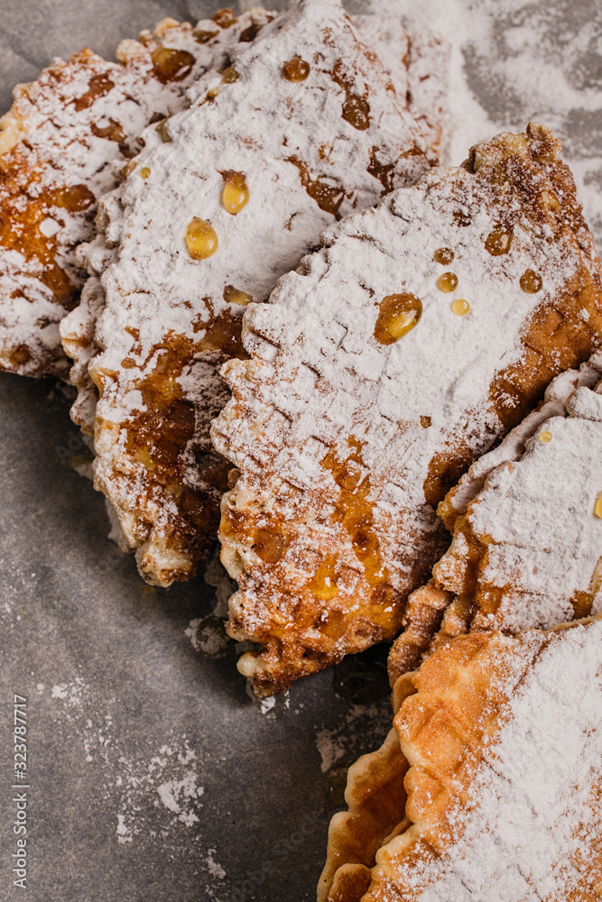 Fototapeta premium Fresh-baked waffles with powdered sugar and honey for breakfast