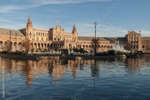 General view of the Plaza de España in Seville at sunset with fountains and water channels in the foreground.