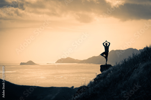 Body  mind health and balance concept. Man meditating on a mountain top at sunset. 