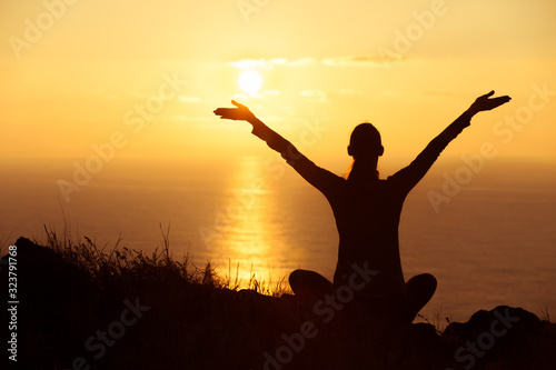 People wellness, feeling happy and carefree. Happy young woman with arms up to the sunset sky facing the ocean view. 
