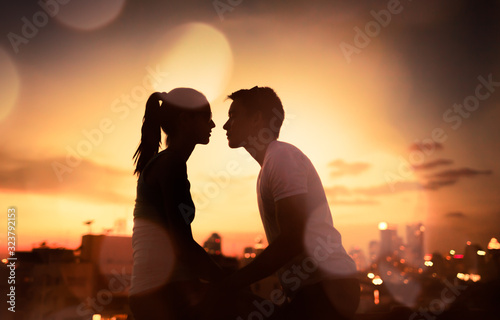 Фотография Romantic young couple kissing in the city at sunset.