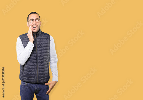 Concerned young man with a toothache gesture