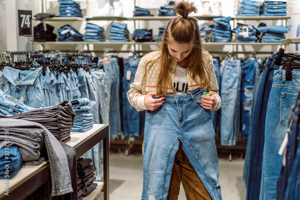 Woman choosing jeans in clothing store. teen girl buys jeans in the mall.  Stock Photo
