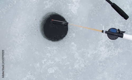 Winter fishing. Fishing rod stands on the ice. Fishing theme