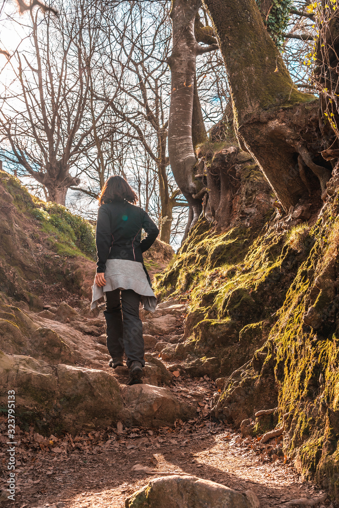A young girl in the mud ramps of the trail of Mount Adarra in Guipuzcoa with sunshine above. Basque Country