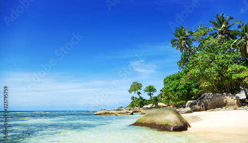 View at amazing tropical beach with beautiful white sand , crystal blue ocean and island at background. Space for text