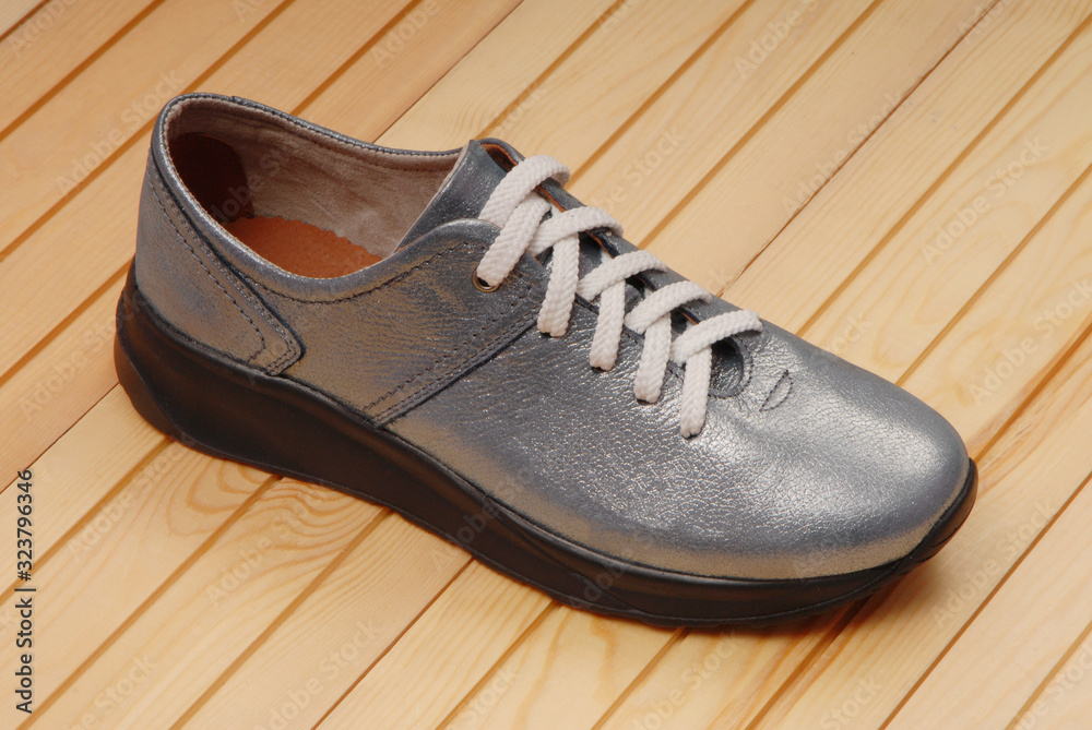 silver-colored boot is on yellow backdrop, leather blue footwear, silver-colored boot is on yellow backdrop, leather blue footwear,