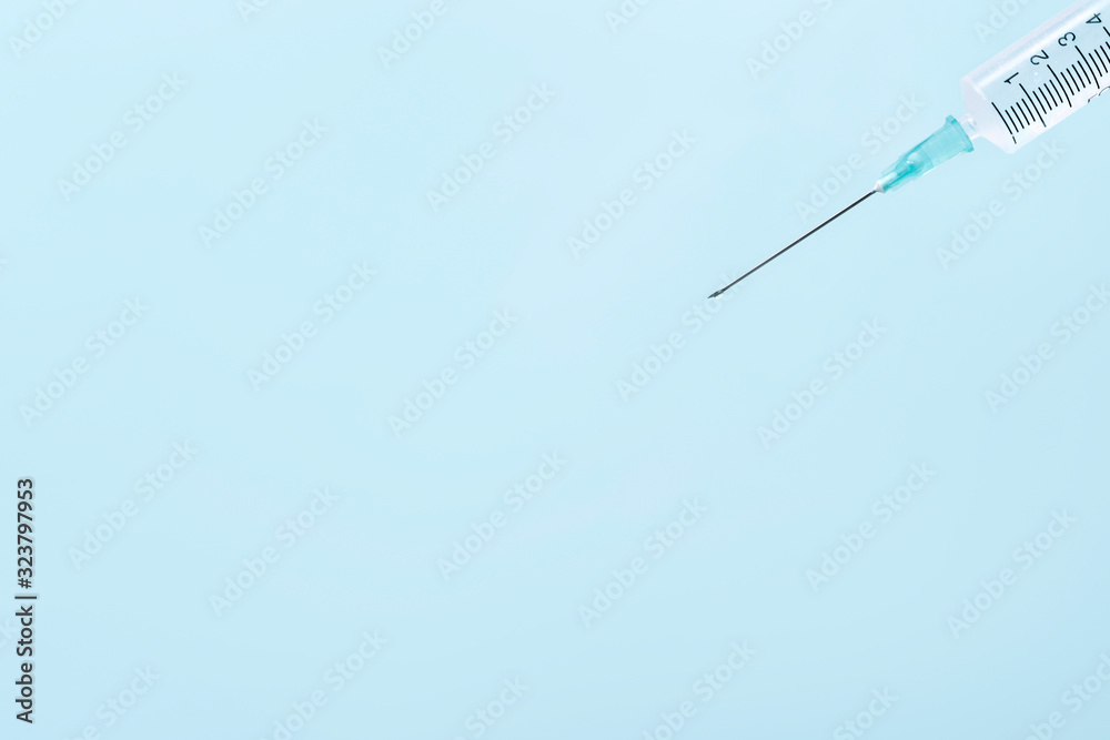 Medical syringe for vaccines on a blue background. Syringe needle closeup Medical syringe for vaccines on a blue background. Syringe needle closeup