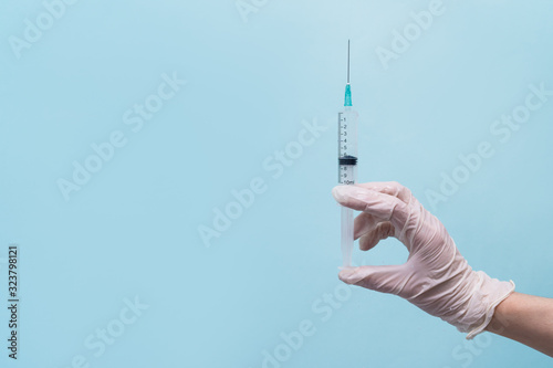 Syringe with a needle on a blue background. Acute medical needle. Nurse holds an injection syringe.