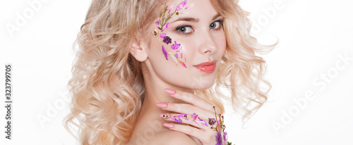 Cosmetics and manicure. Close-up portrait of attractive woman with dry flowers on her face, pastel color of nail design, perfect make-up and skin. Trendy
