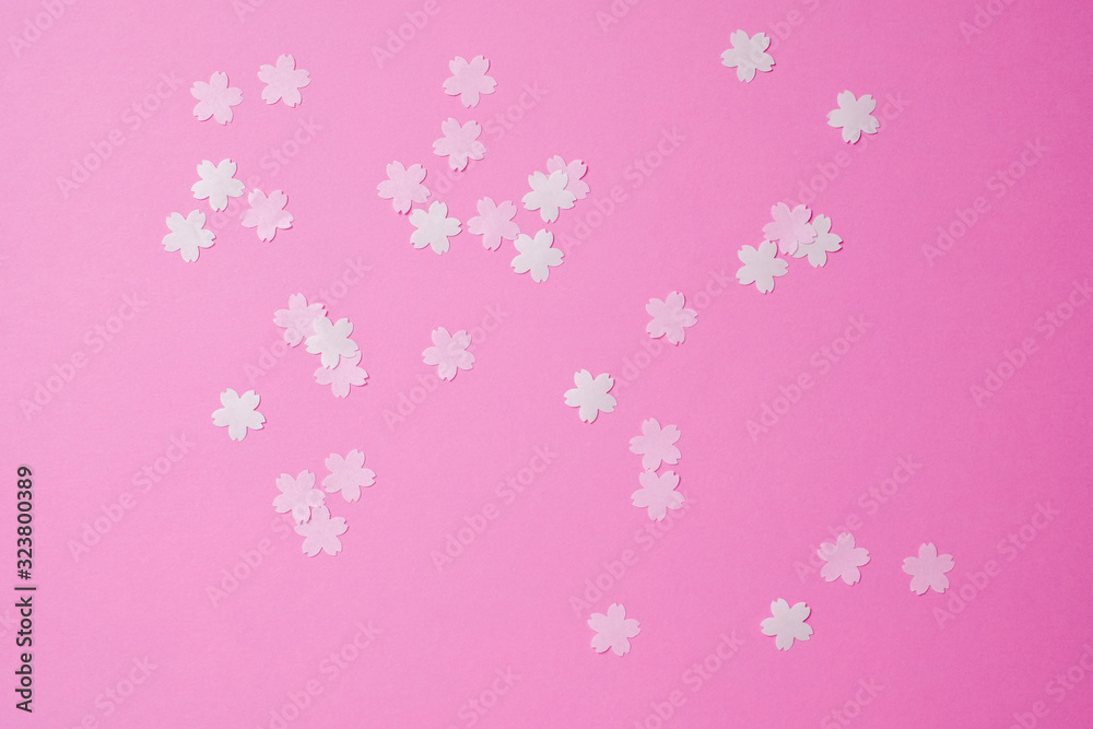ピンクのバック紙の上に散らばった桜の花の切り絵