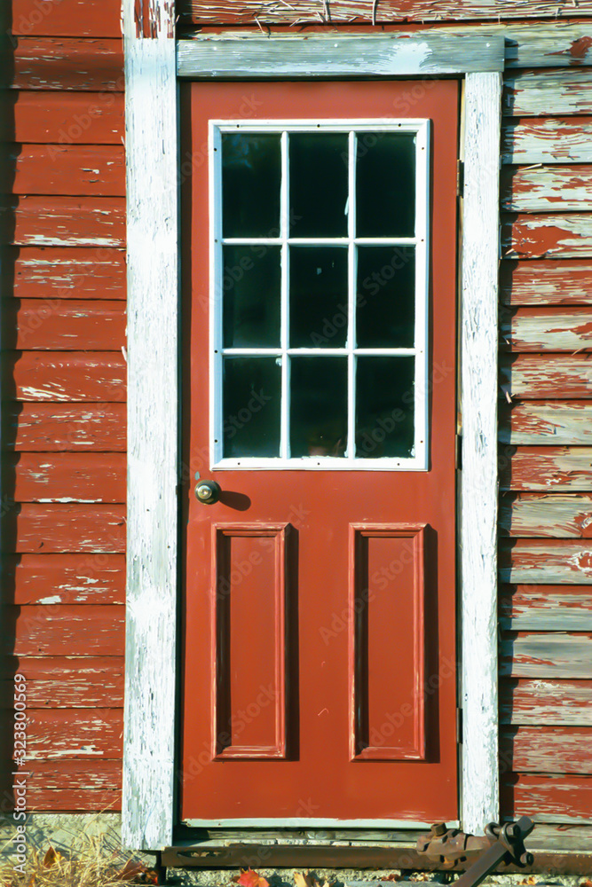Old red wooden door with window panes. Old brick building with weathered doorway Old red wooden door with window panes. Old brick building with weathered doorway