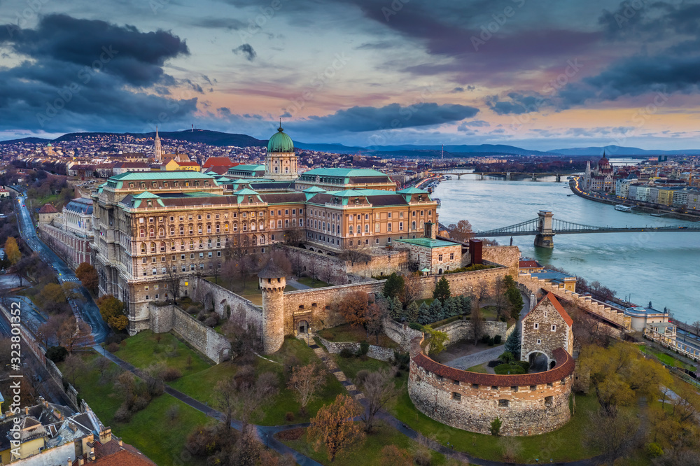 Budapest, Hungary - Aerial panoramic view of Buda Castle Royal Palace and Szechenyi Chain Bridge at dusk with colorful clouds and sky