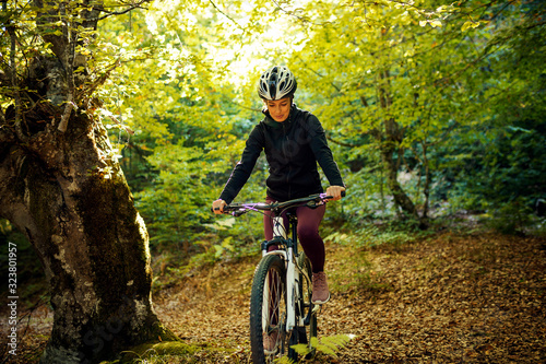 Female cyclist riding mountain bike in forest