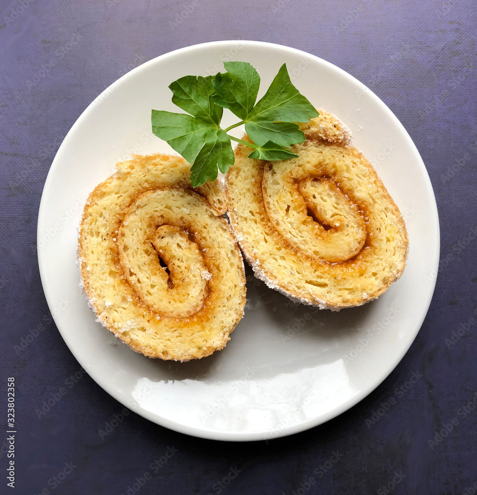Swiss roll filled with apricot jam and sprinkled with icing sugar.
