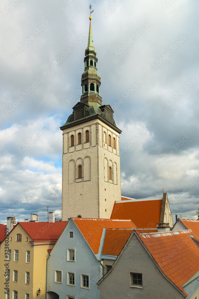 105-meter tall bell tower of the St. Nicholas Church seen behind the colourful buildings in the old town on an autumn day in Tallinn, Estonia, Europe. The former church houses the Niguliste Museum.