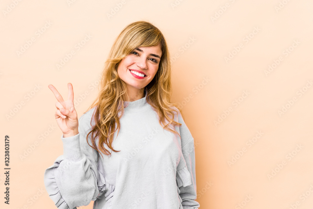 Young blonde caucasian woman joyful and carefree showing a peace symbol with fingers. Young blonde caucasian woman joyful and carefree showing a peace symbol with fingers.