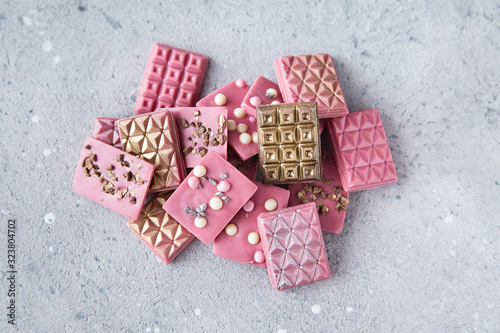 Broken and shattered pieces of ruby pink chocolate on ligth grey background.