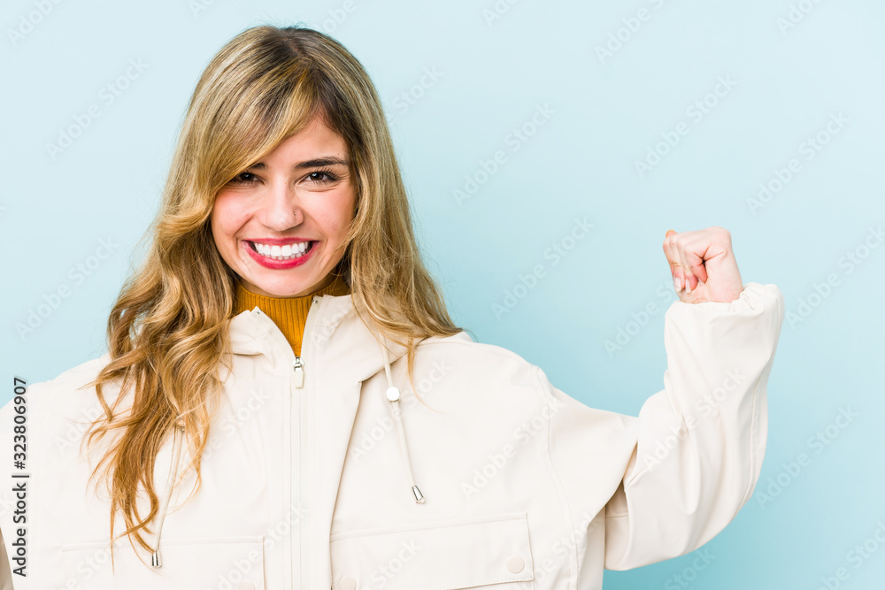 Young blonde caucasian woman showing strength gesture with arms, symbol of feminine power Young blonde caucasian woman showing strength gesture with arms, symbol of feminine power
