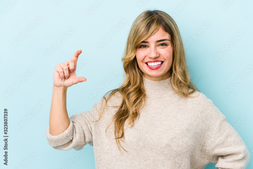 Young blonde caucasian woman holding something little with forefingers, smiling and confident. Young blonde caucasian woman holding something little with forefingers, smiling and confident.