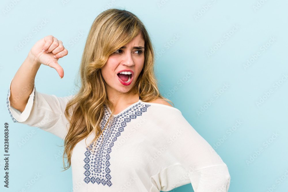 Young blonde caucasian woman showing thumb down and expressing dislike. Young blonde caucasian woman showing thumb down and expressing dislike.