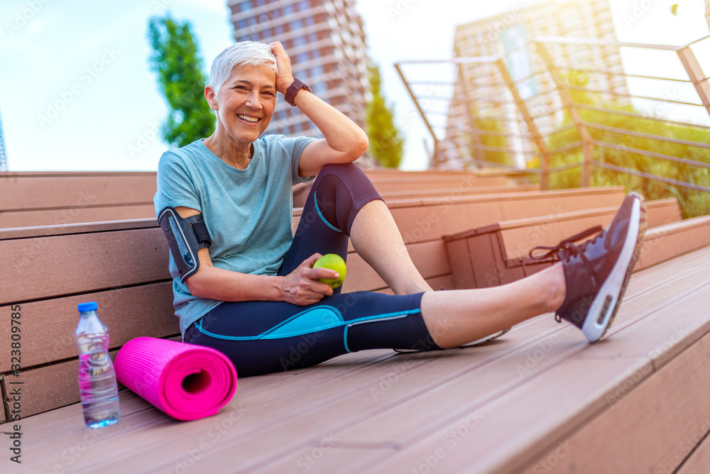 Senior woman eating apple after exercise. Happy mature woman
