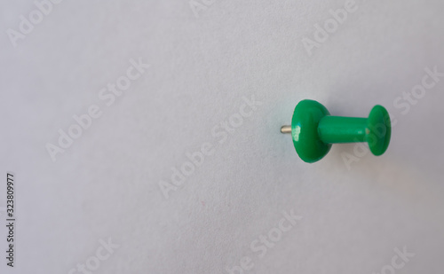 Green pin, attached to a white empty paper, oriented to the right
