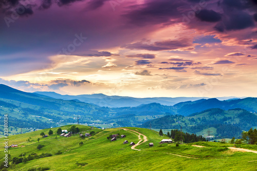 Summer mountain rural landscape, awesome evening sunset view on village and meadow.