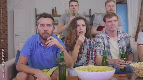 Anxious friends attentively watching fottball match on TV together photo