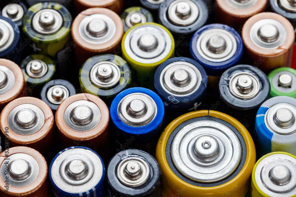 Close up of positive ends of colorful discharged batteries of different sizes and formats, top view, selective focus. Used alkaline battery. Hazardous garbage concept Close up of positive ends of colorful discharged batteries of different sizes and formats, top view, selective focus. Used alkaline battery. Hazardous garbage concept