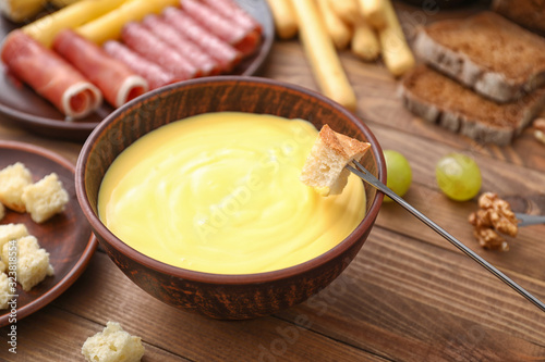 Dipping of crouton into cheese fondue on table