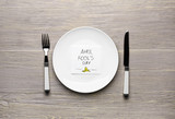 Dinnerware and napkin with text APRIL FOOL'S DAY on wooden table