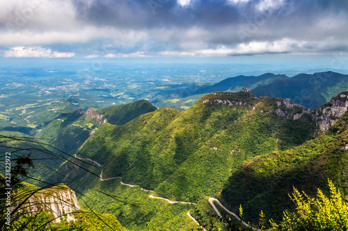 A cloudy Mountain range view from the "Serra do Rastro". A beautiful panoramic view with green mountains, a serpentine road and green pastures.