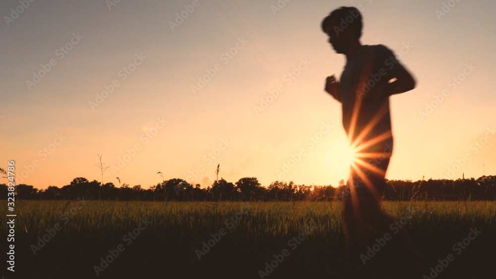 Silhouette of man running sprinting  during outdoor workout with sunset background