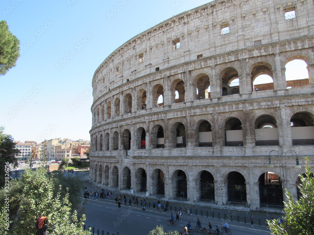 Exterior view of the Colosseum, also known as the Flavian Amphitheater, located in Rome, Italy with blue sky in the background 