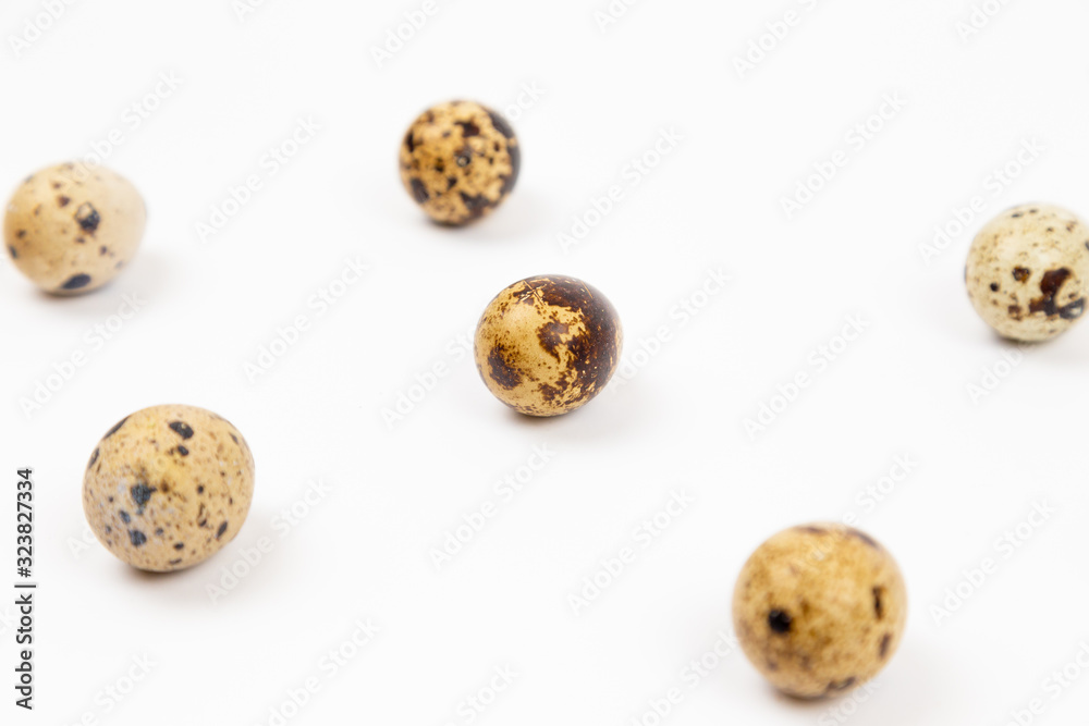 Uncooked scattered Quail eggs on white background top view, healthy food concept