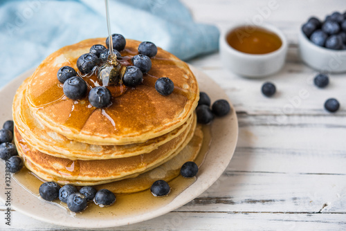 Close up of a stack of fluffy pancakes with maple syrup poured over them