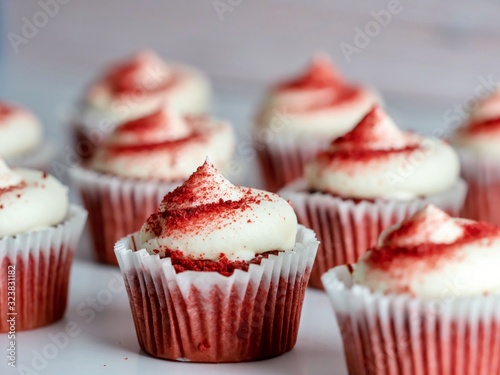 Red velvet cupcakes decorated with white cream cheese frosting and red powder!  Delicious and beautiful baked goods!