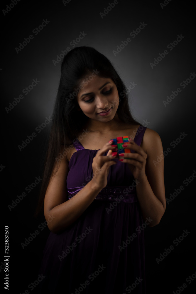 Fashion portrait of young and attractive Indian Bengali brunette girl in purple western dress with small cherry plant in hand in front of black studio background. Indian lifestyle. Fashion portrait of young and attractive Indian Bengali brunette girl in purple western dress with small cherry plant in hand in front of black studio background. Indian lifestyle.